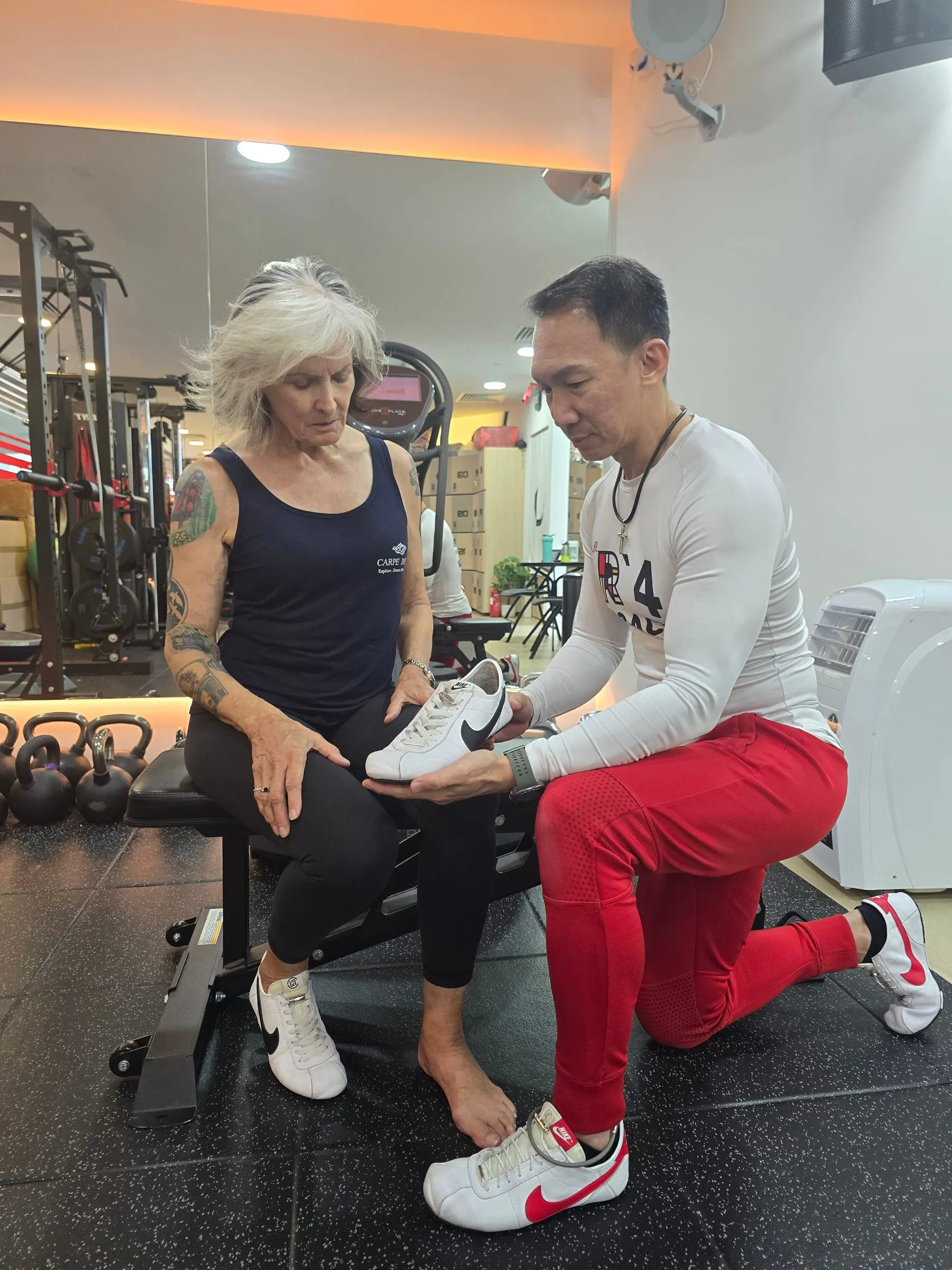 Nelson Chong reviewing a client's footwear during a personal training session at FTI